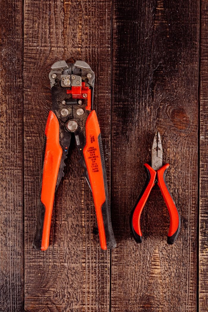 Flat lay of wire stripper and pliers on a wooden surface. Perfect for DIY projects.